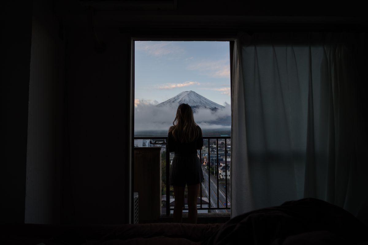 霧の朝、バルコニーから富士山を見る後ろ姿