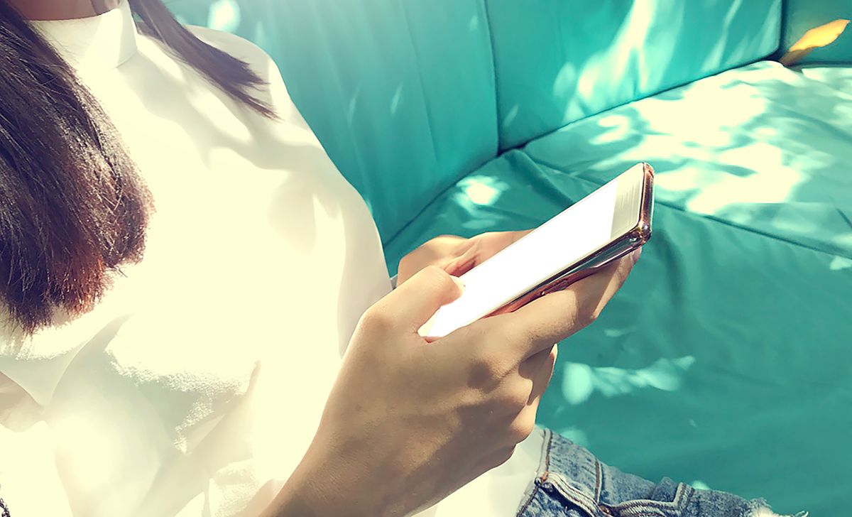 日差しの差すソファでスマホを持つ手元