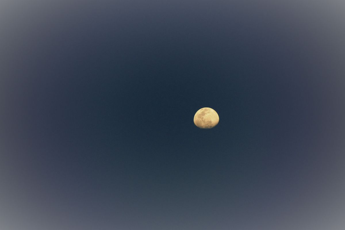 暗い青い夜空に浮かぶ黄色い月