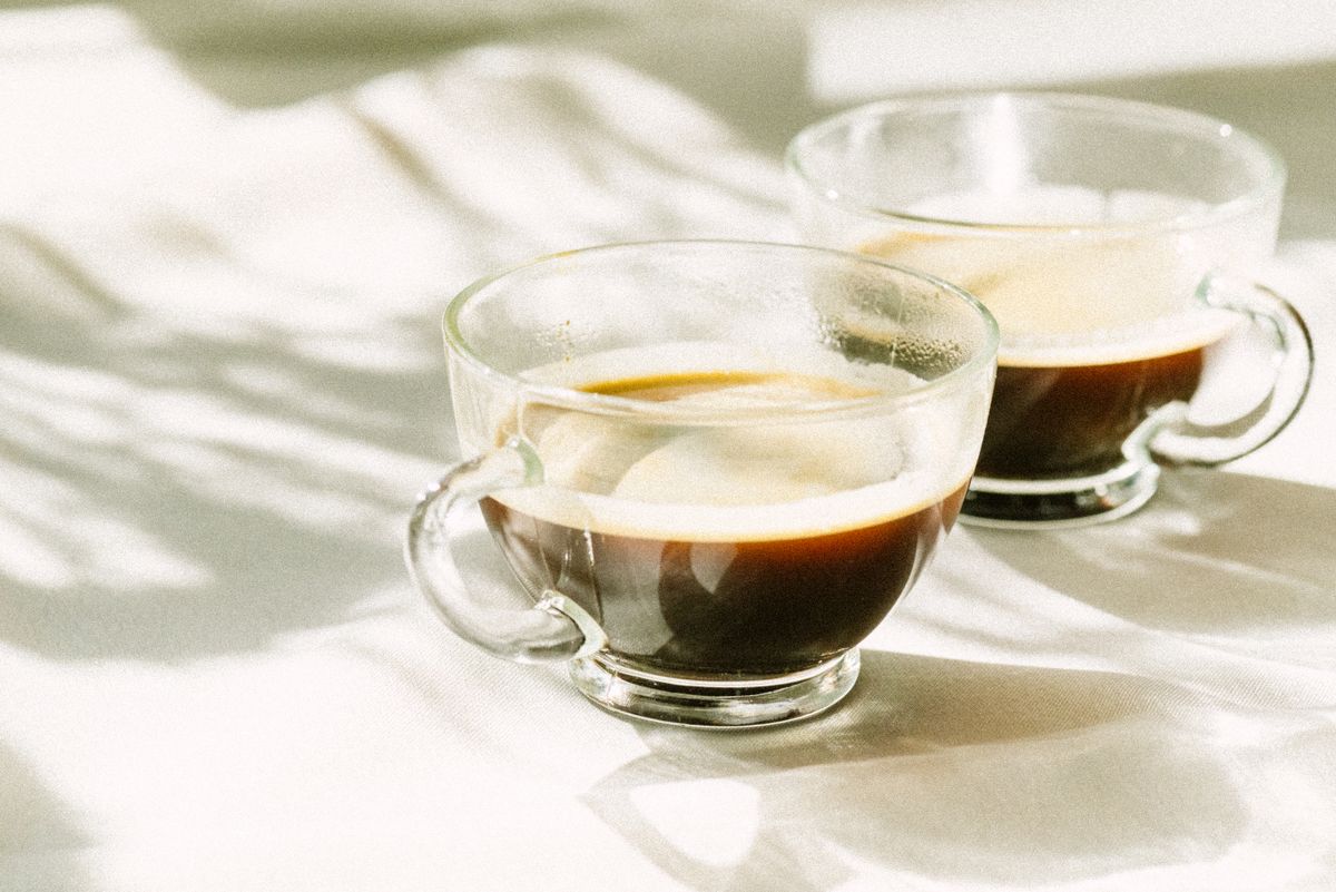 朝の光が差す白いテーブルの上の2つのコーヒー
