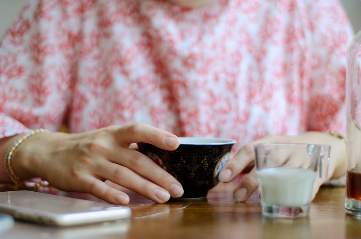 スマホとカップに手を添える女性の手元