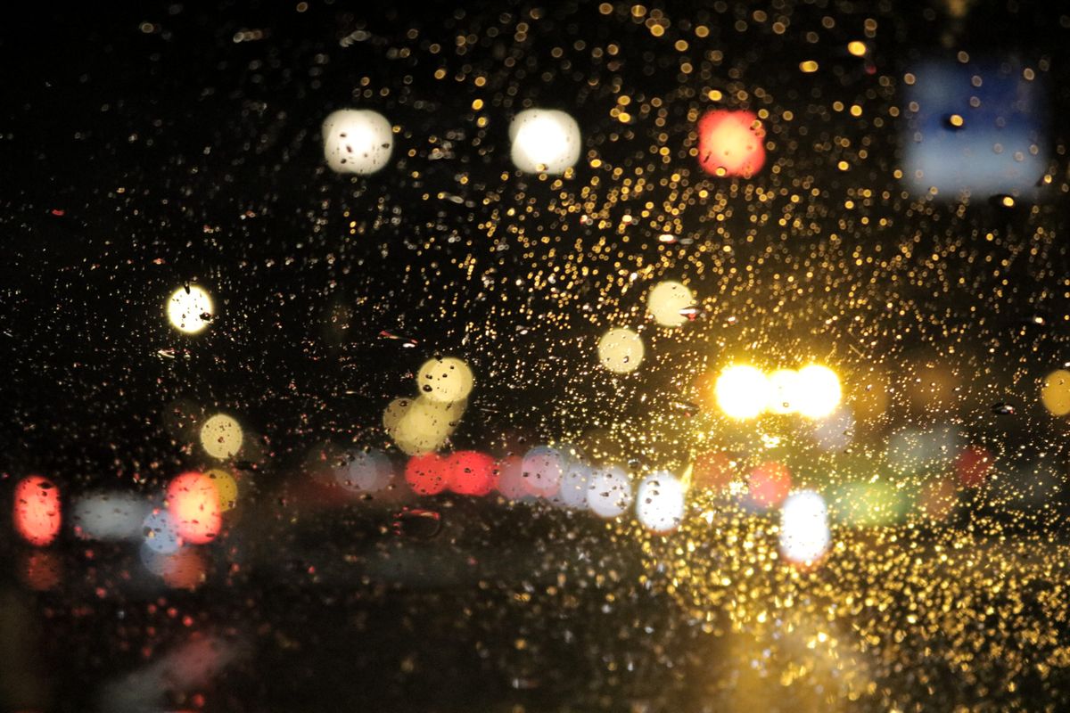 雨粒のついた窓越しににじむ夜の街明かり