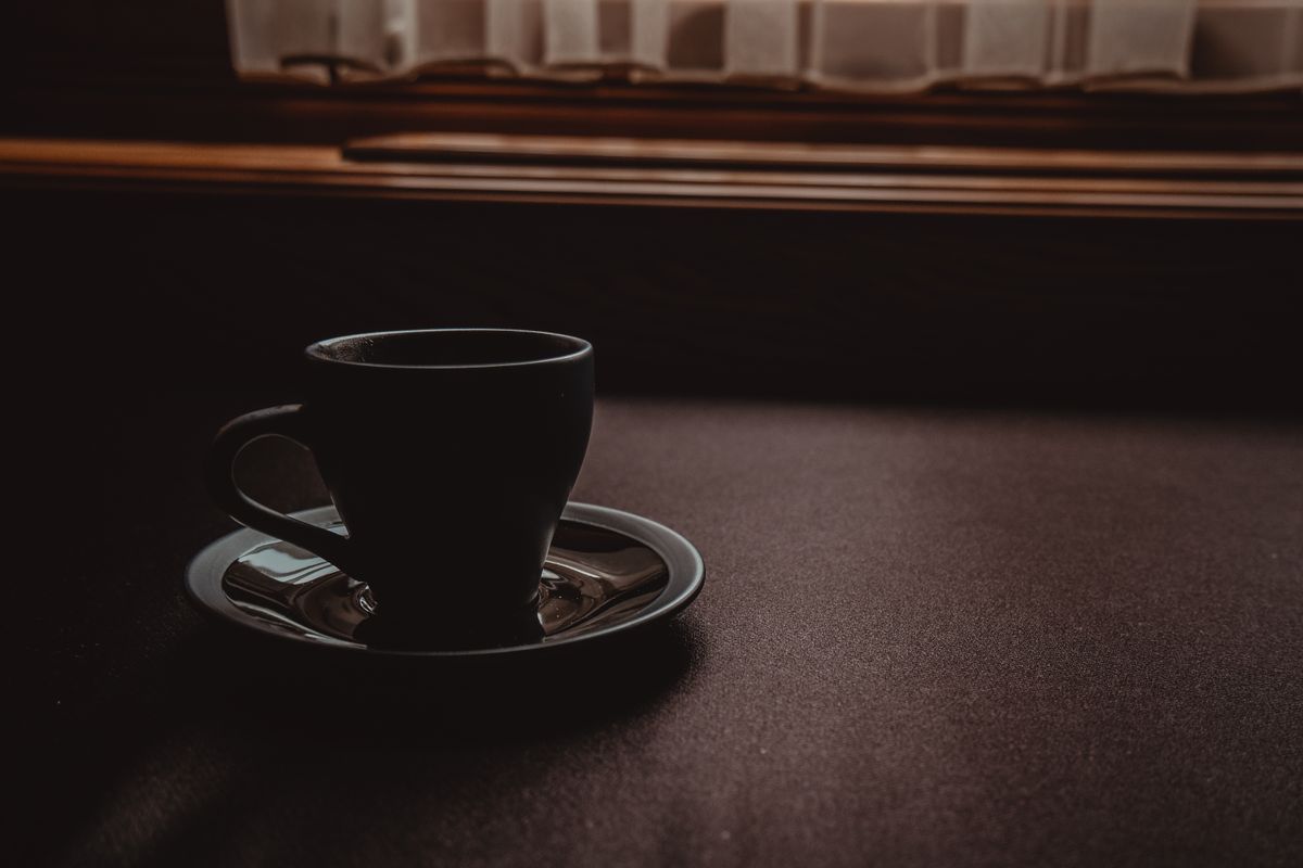 窓辺のテーブルに置かれた黒いコーヒーカップ