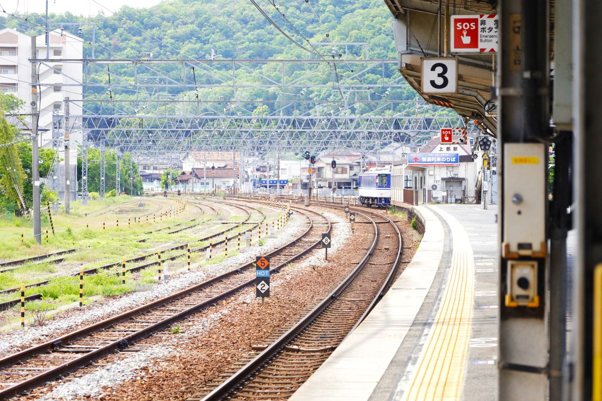 山を背景に線路が延びる駅のホーム